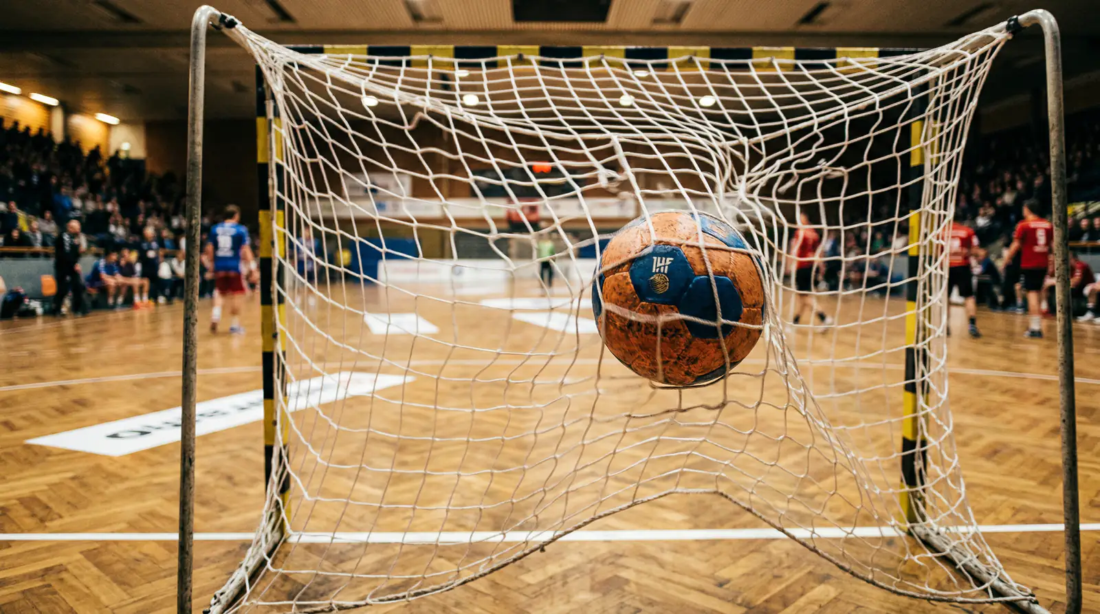 Handball fliegt ins Tornetz bei einem Bundesliga-Spiel in einer vollen Halle
